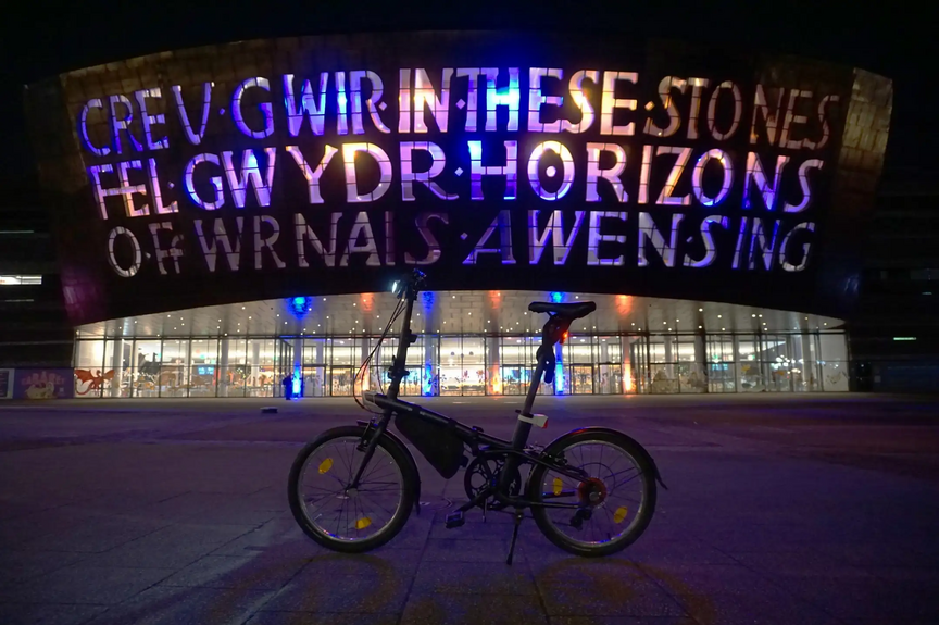 Faltrad vor dem Wales Millennium Centre Ein Faltrad steht bei Dunkelheit vor dem Wales Millennium Centre und ist von der linken Seite zu sehen.